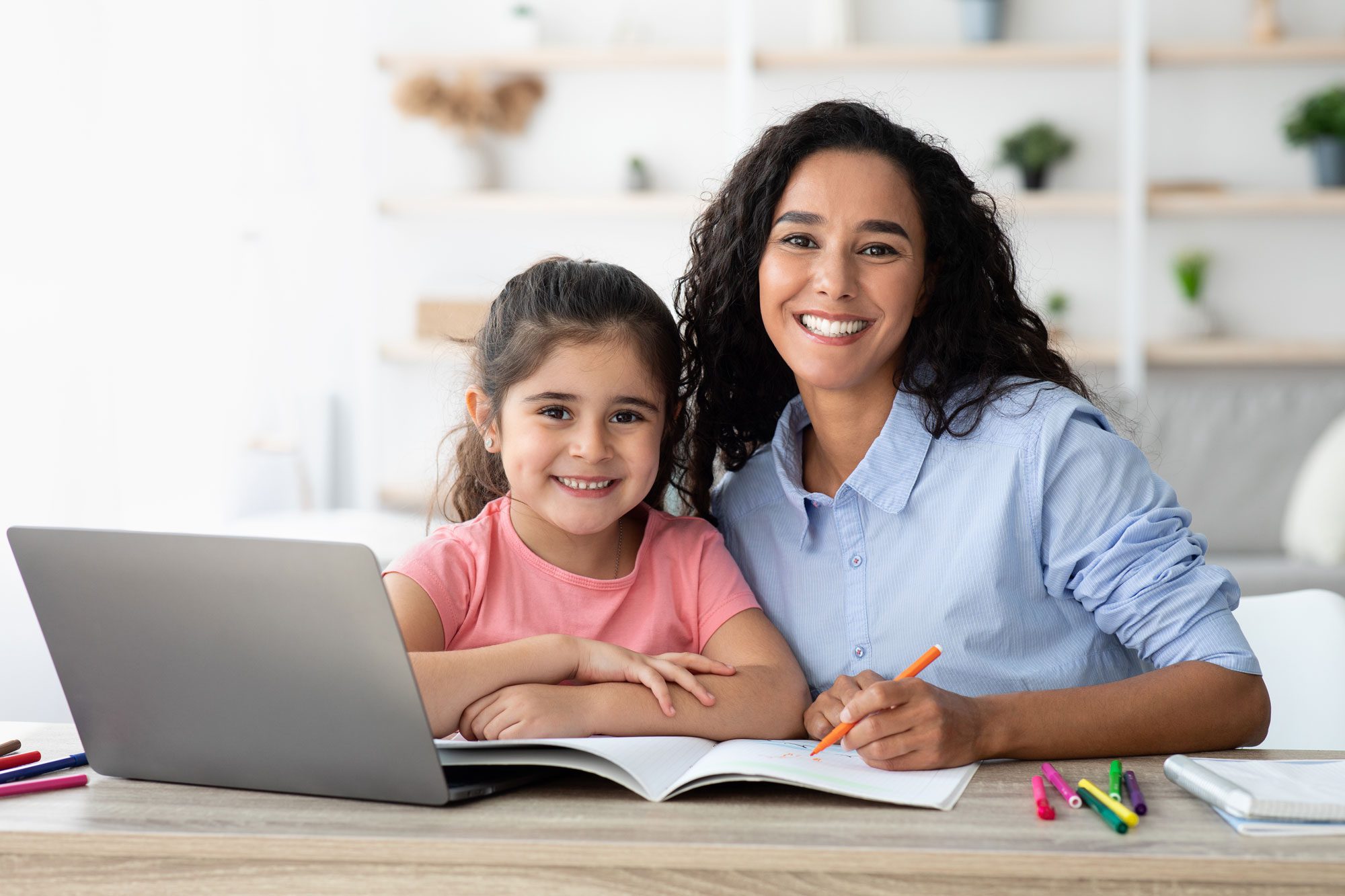 smiling mother and daughter doing schoolwork