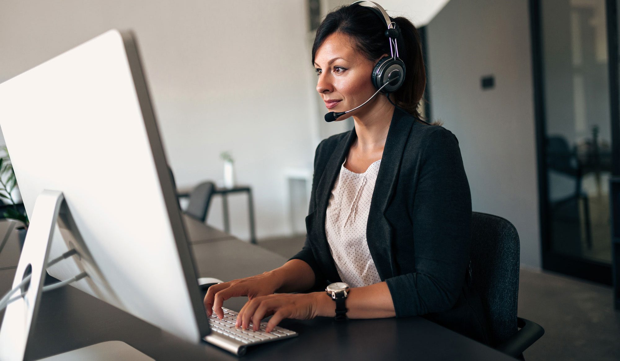 Businesswoman working with headset on computer.